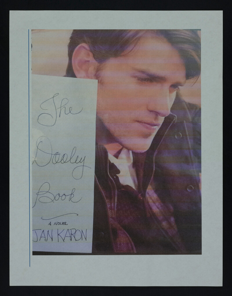 Photograph of young man looking pensively to the side. Paper in frame alongside photo says: The Dooley Book, A Novel, Jan Karon