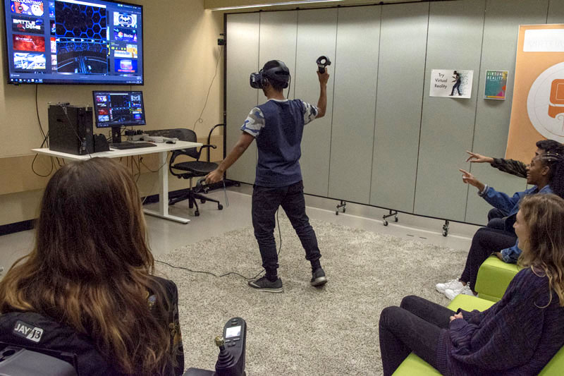 A man is using a VR machine while other students look on.