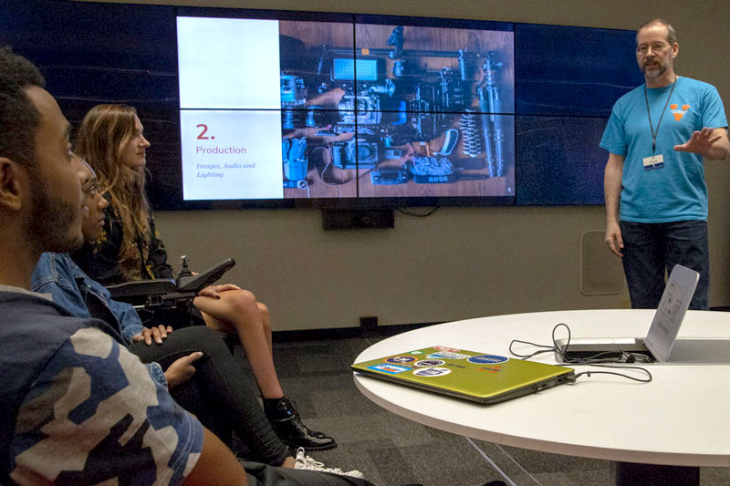 An instructor explains a presentation to a group of students.